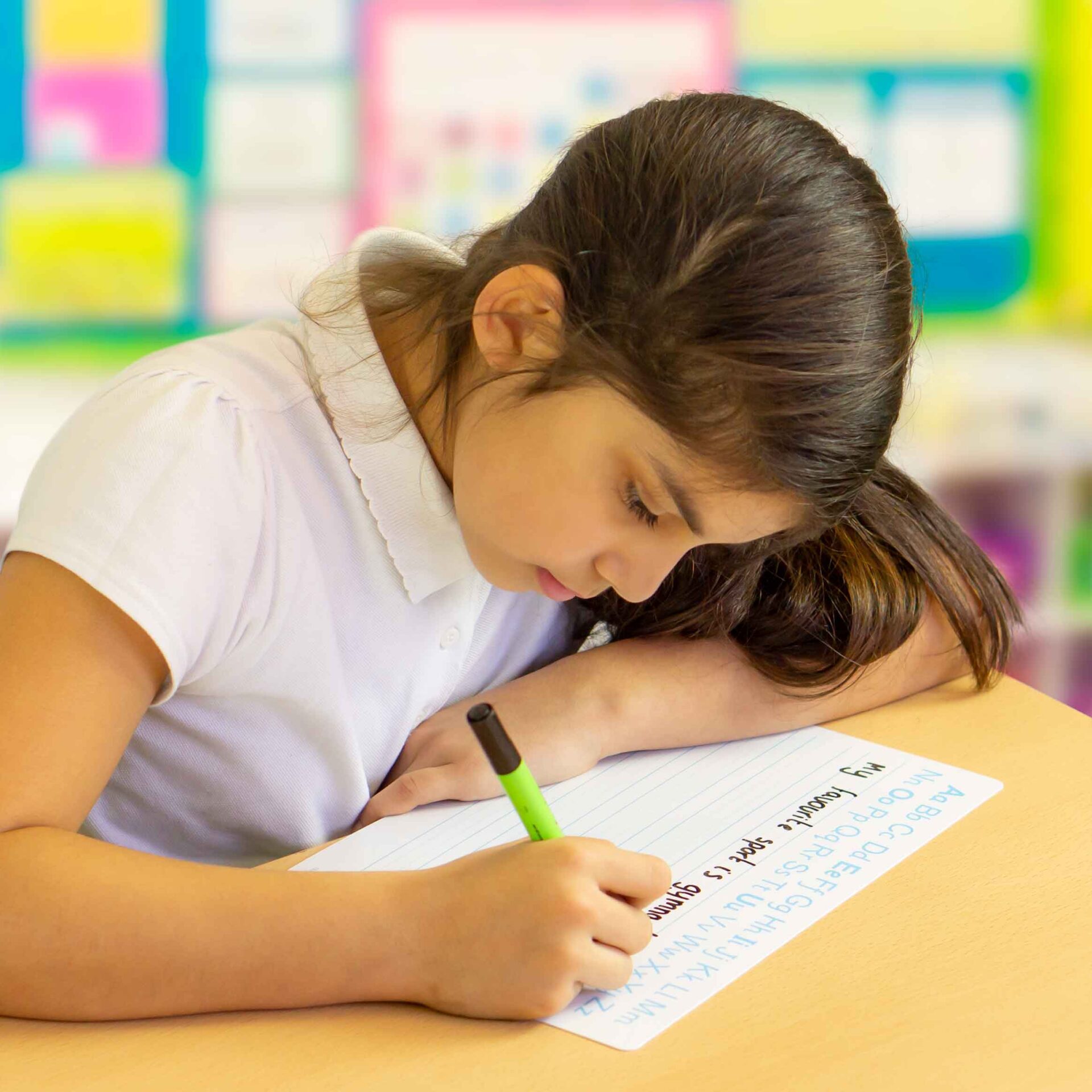 Young girl in a classroom using an SDP marker and a handwriting mini whiteboard.